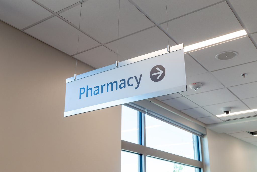 Suspended interior wayfinding sign directing visitors to the pharmacy at Sage Memorial Hospital