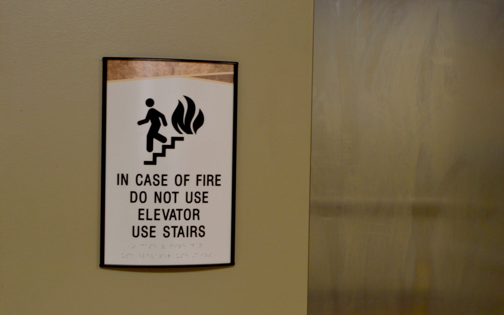 ADA-compliant elevator life safety sign stating in case of fire do not use elevator, use stairs