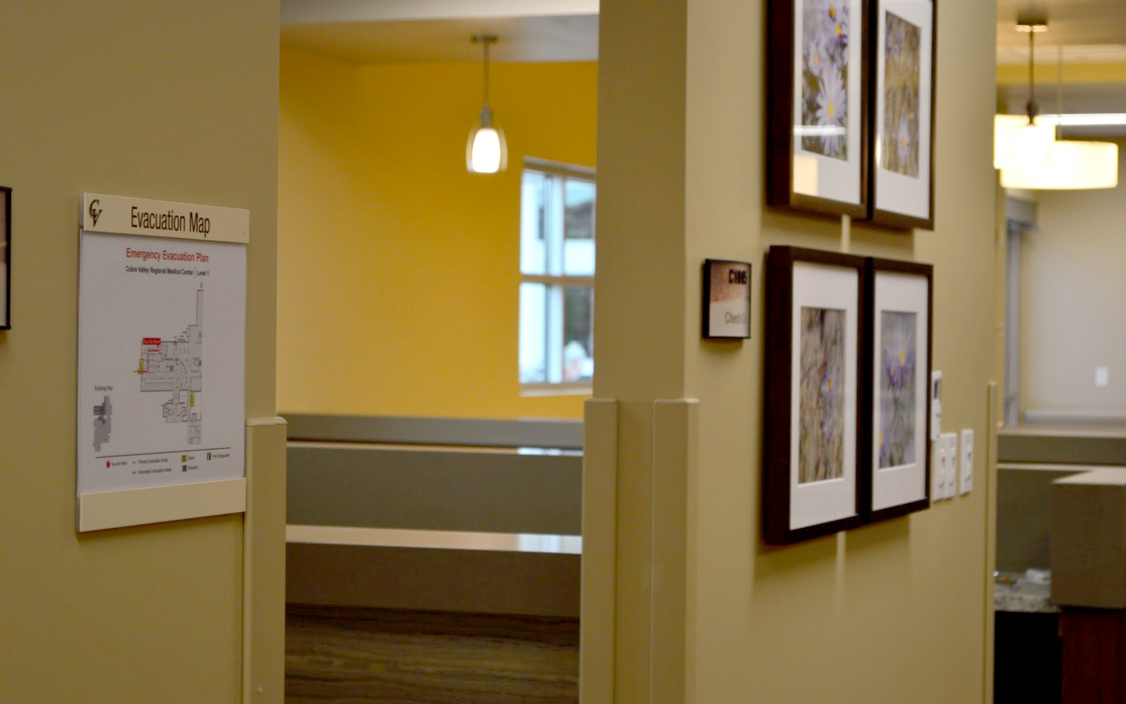 Interior evacuation map displayed in a custom wall-mounted document holder within a hospital corridor