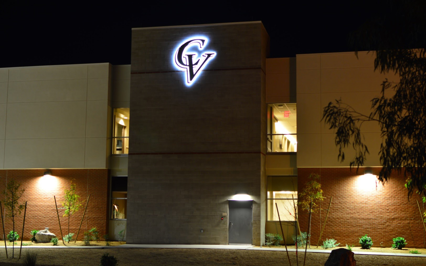 Nighttime view of the halo-illuminated Cobre Valley Regional Medical Center logo mounted on a masonry tower