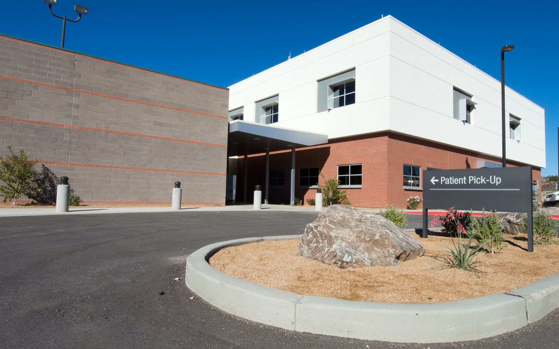 Post-and-panel hospital sign directing visitors toward the main entrance, clinics, pharmacy and patient pick-up