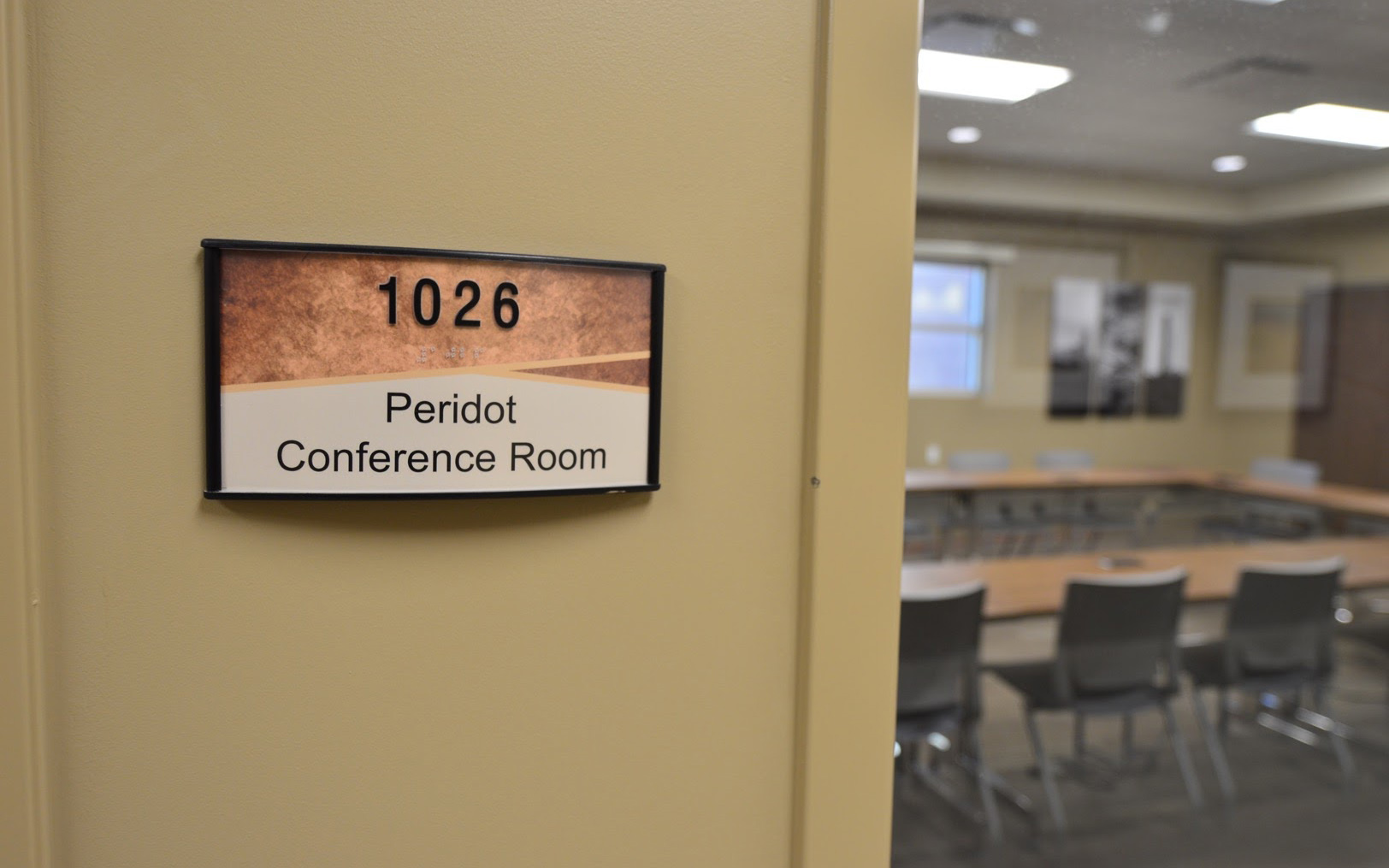 Close-up of an ADA-compliant room sign identifying the Peridot Conference Room with tactile text and Braille