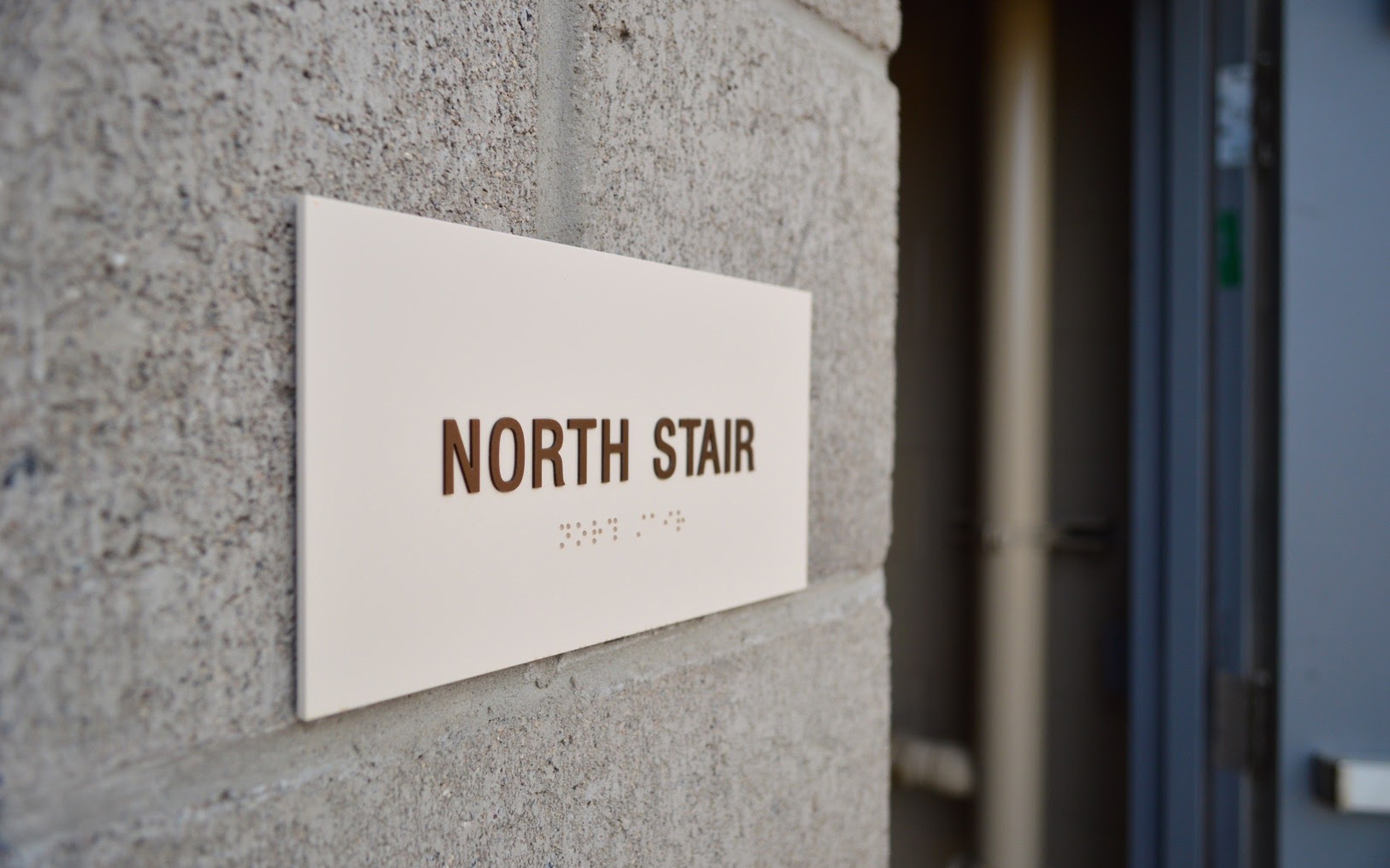 Exterior ADA-compliant sign identifying the North Stair with tactile lettering and Braille