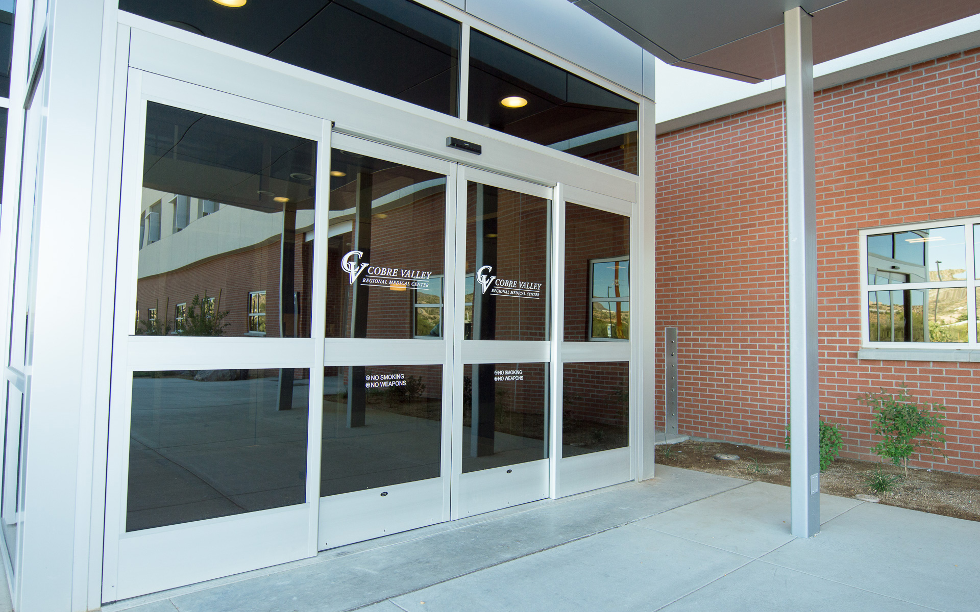 White vinyl graphics on glass entrance doors featuring the Cobre Valley Regional Medical Center logo and regulatory notices