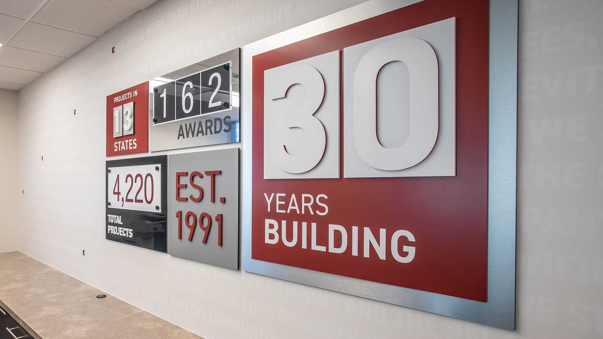 Updateable wow wall display at Caliente Construction front desk featuring interchangeable room signage panel in branded office environment