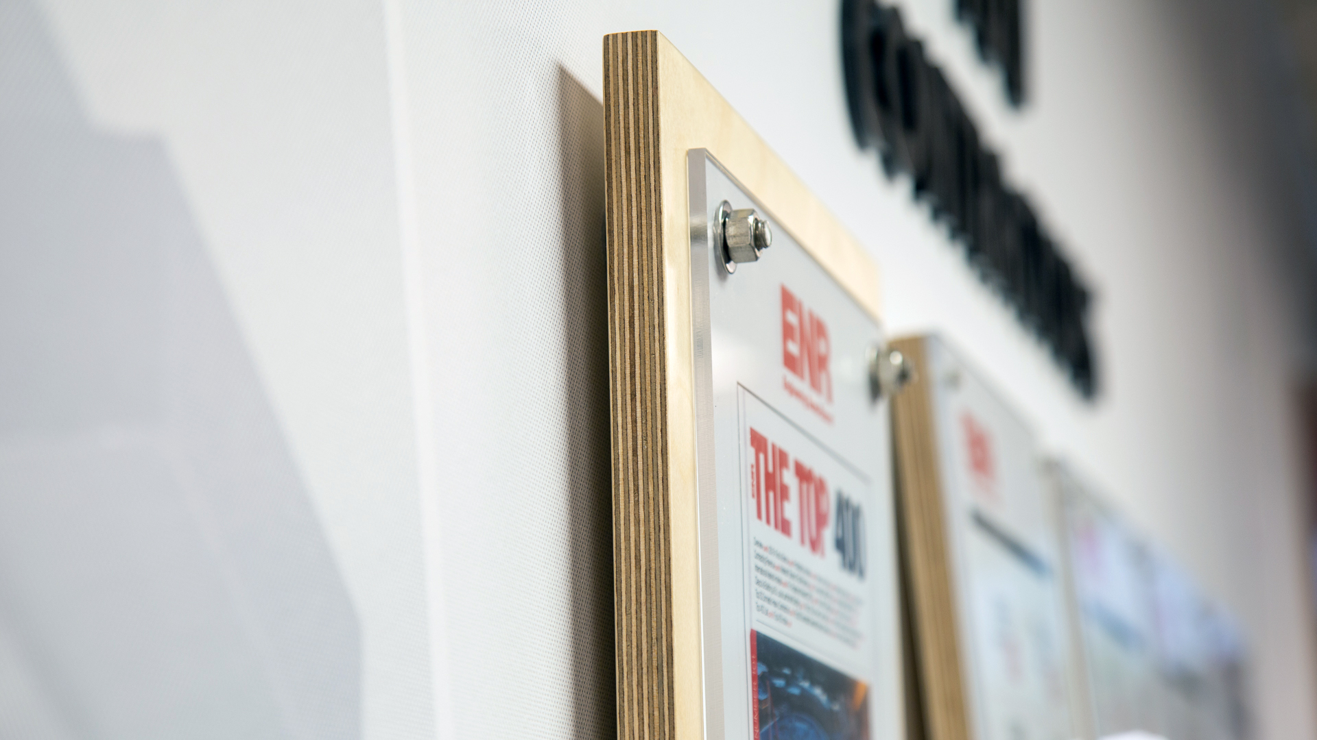 Custom award display detail with stainless steel stand-off mounting in corporate interior