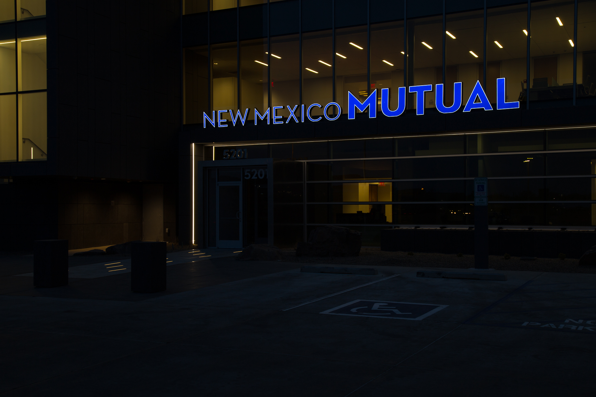 Low light exterior view of illuminated channel letters on corporate building New Mexico Mutual Albuquerque