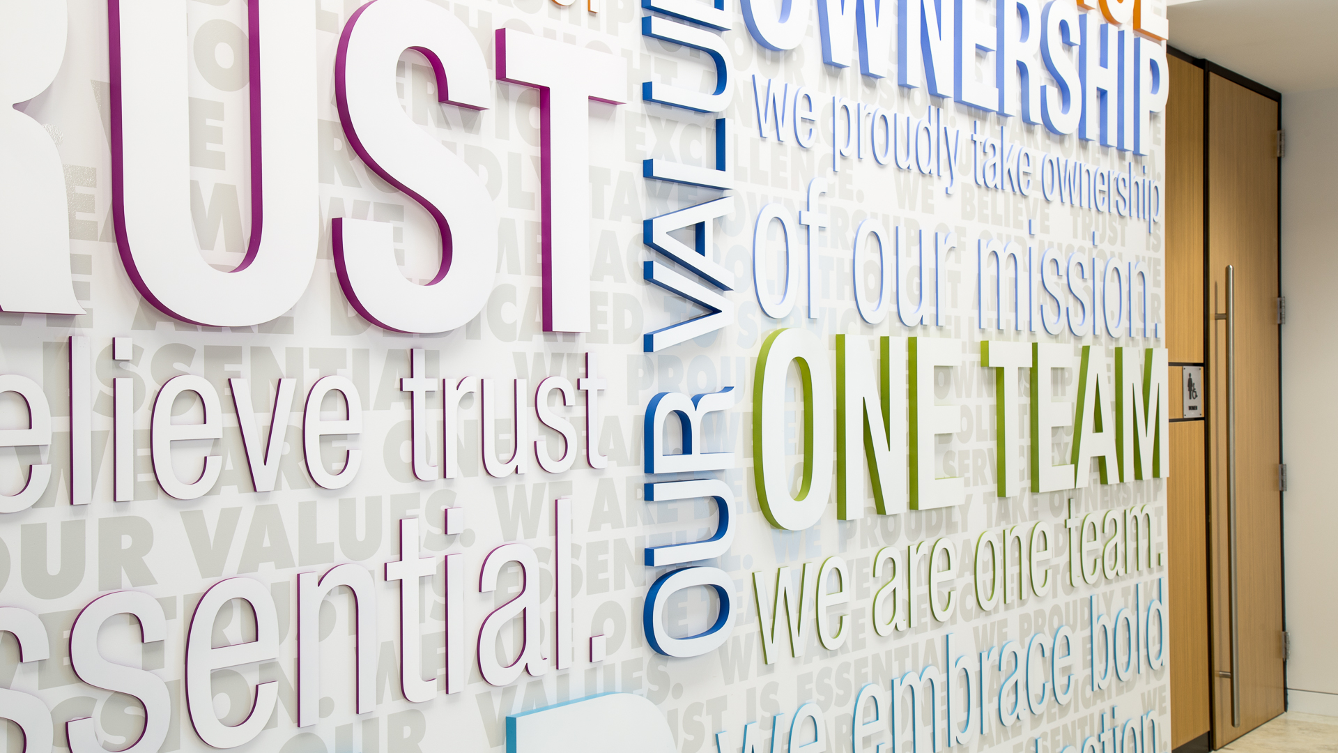 Close up detail of dimensional letters with painted color returns and vinyl graphics on value wall New Mexico Mutual Albuquerque