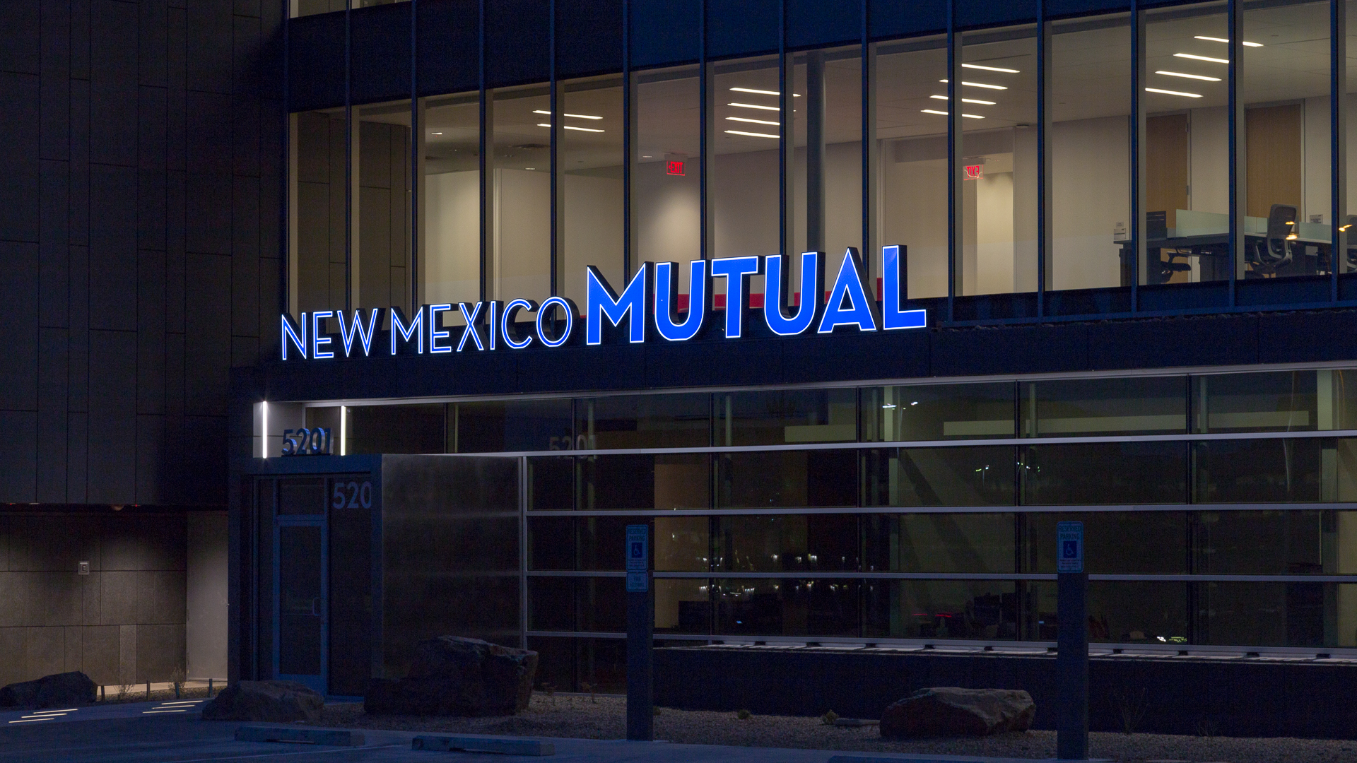 Front face lit channel letters on New Mexico Mutual building at night in Albuquerque with blue illuminated lettering