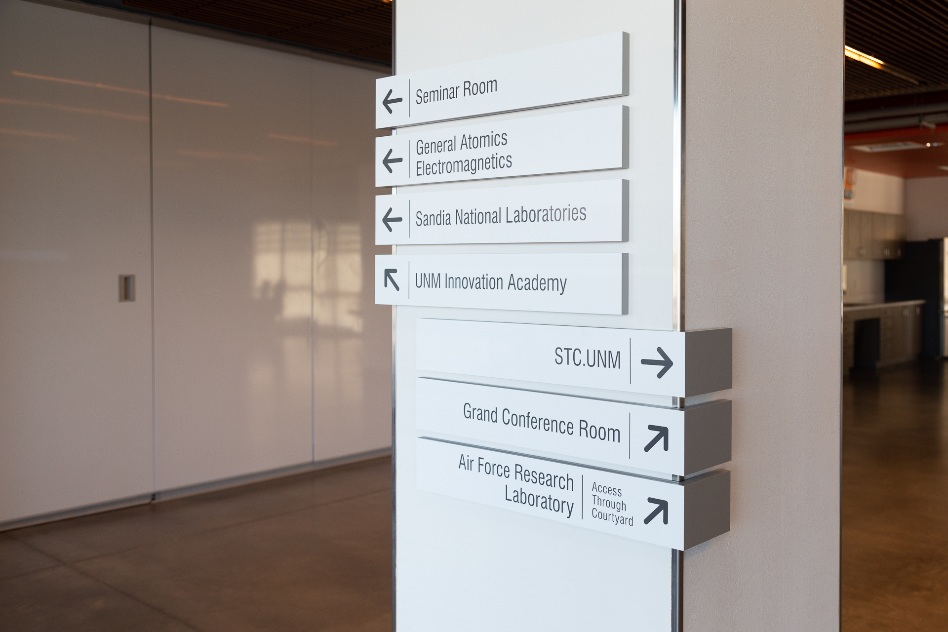 UNM Lobo Rainforest Interior Wayfinding Column-Mounted Directional Signs Interior wayfinding signage at UNM Lobo Rainforest featuring directional signs mounted to a column with vinyl lettering