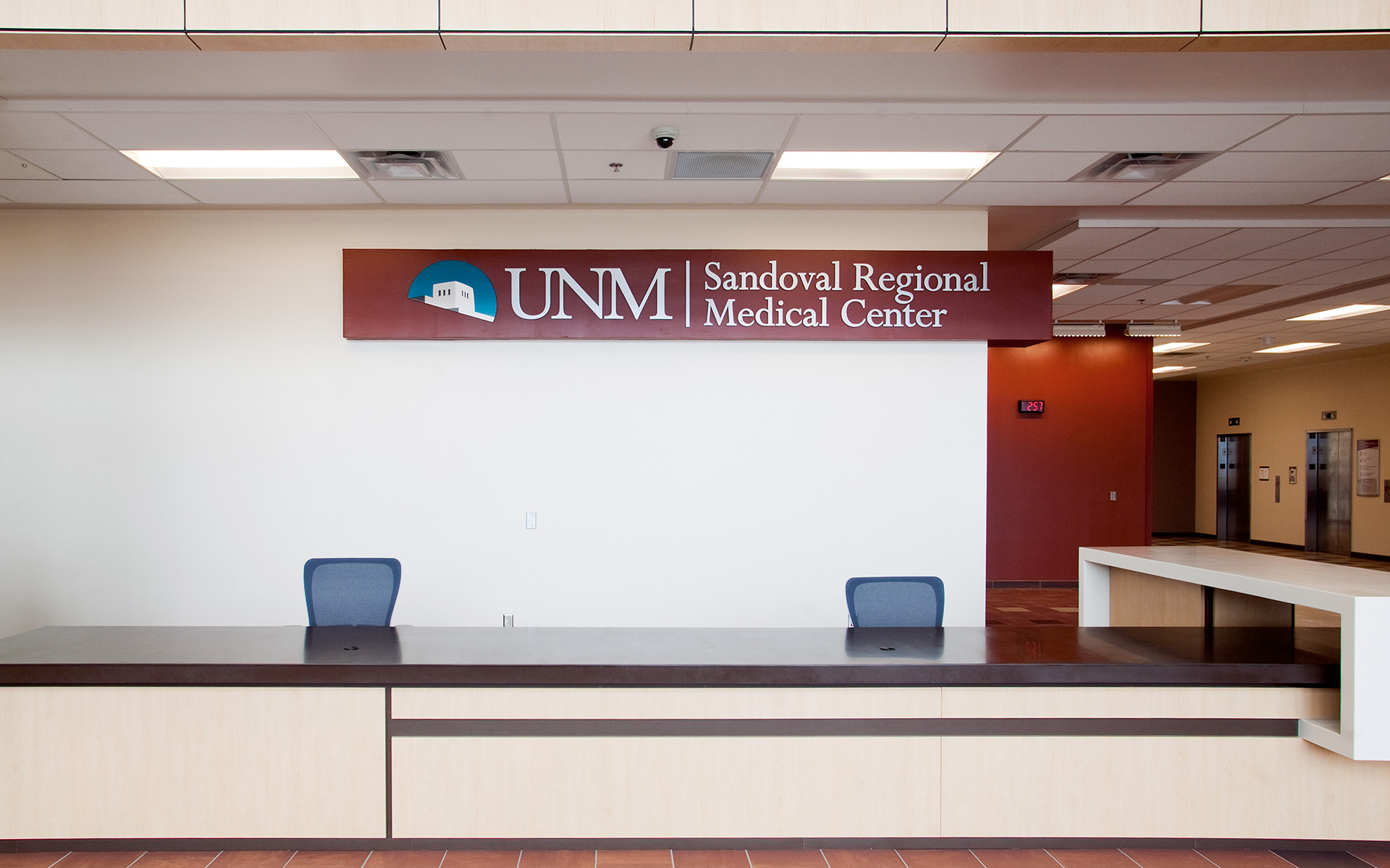 Brushed aluminum dimensional logo at UNM Sandoval Regional Medical Center main lobby reception area