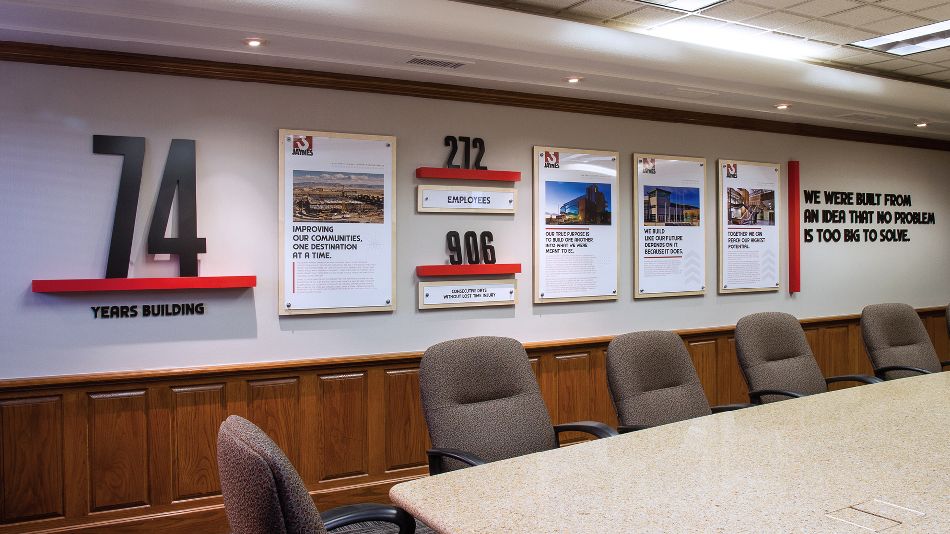 Conference room wall featuring corporate branding display with company statistics and project highlight panels