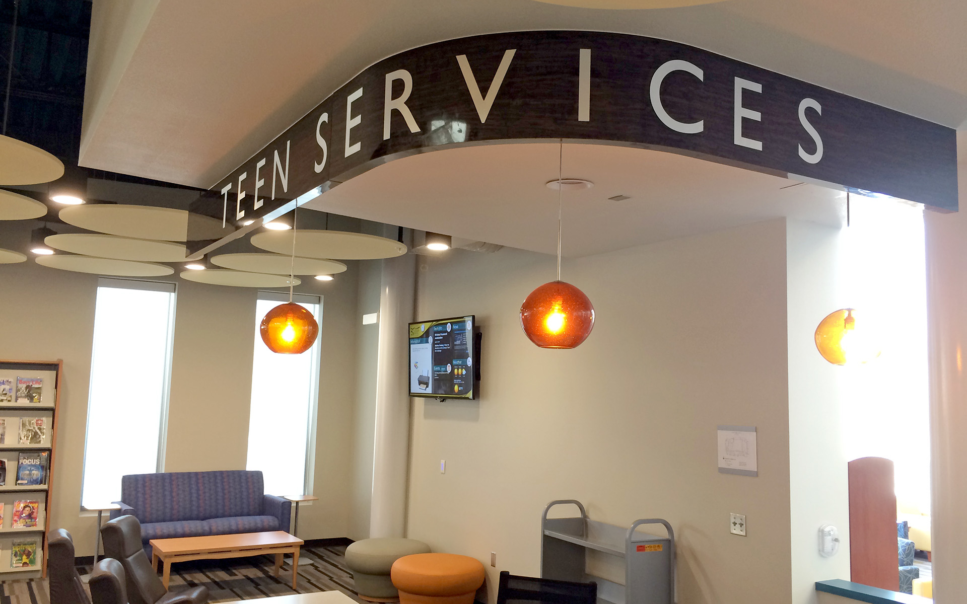 Interior teen services sign on curved wall with dimensional lettering at Artesia Public Library New Mexico