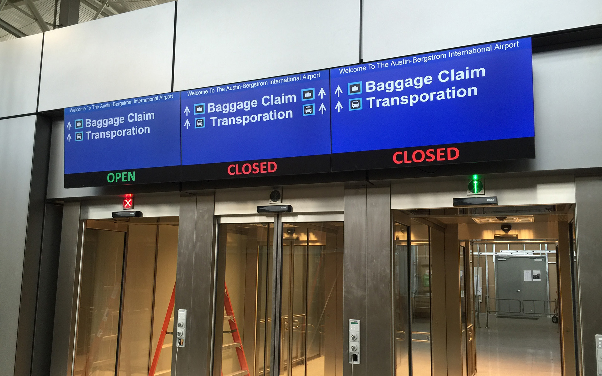 Digital overhead wayfinding sign at Austin Bergstrom International Airport directing passengers to baggage claim and transportation