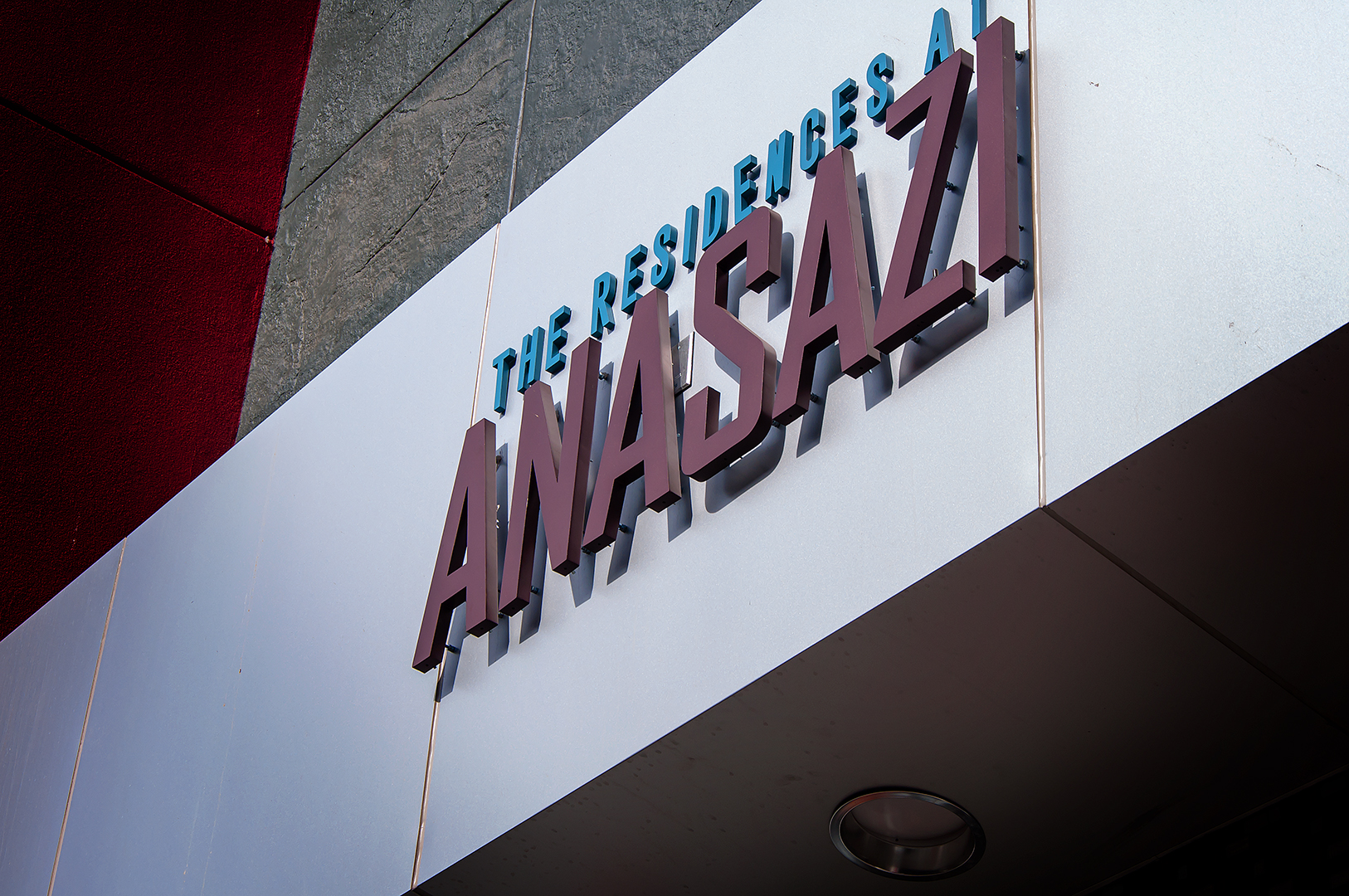 Close-up detail of dimensional letters mounted to building facade showing depth and mounting hardware