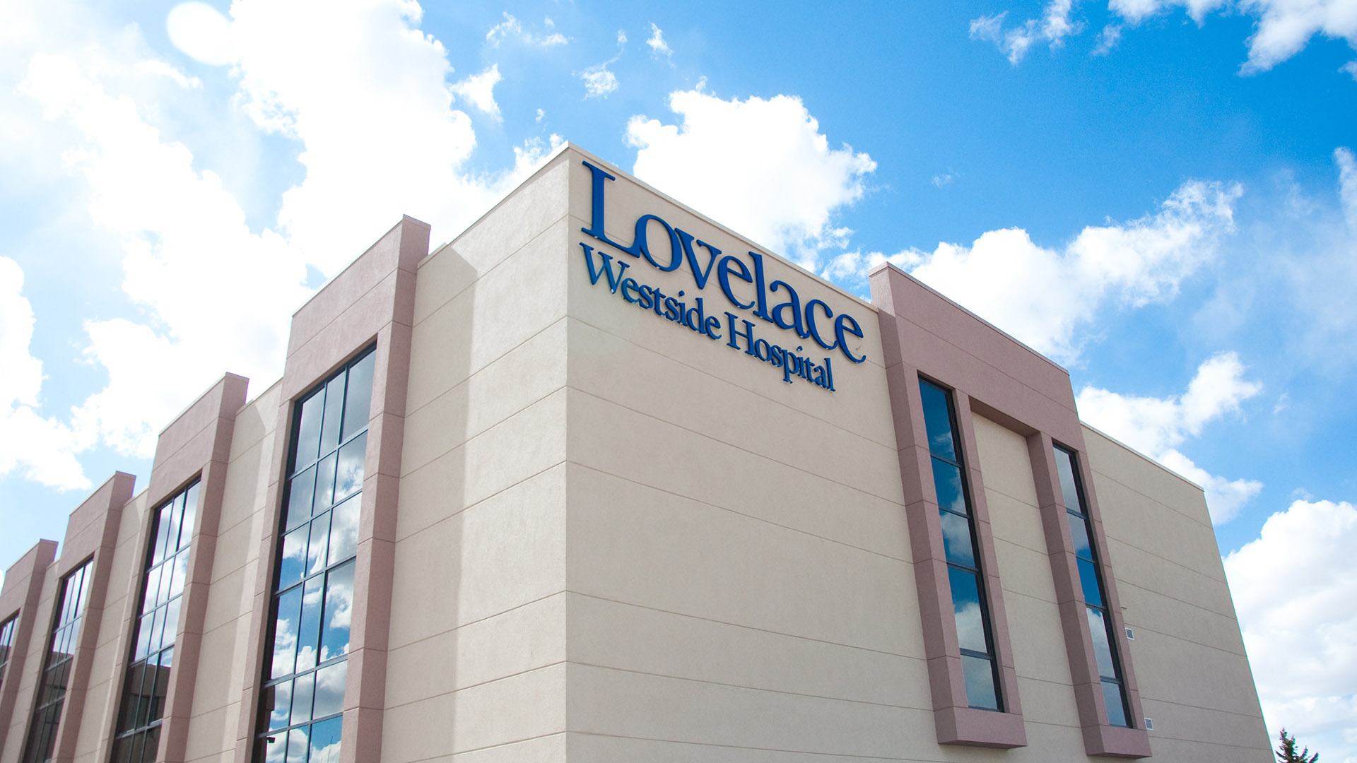 Exterior directional sign indicating hospital entrance with Lovelace Westside Hospital building in background