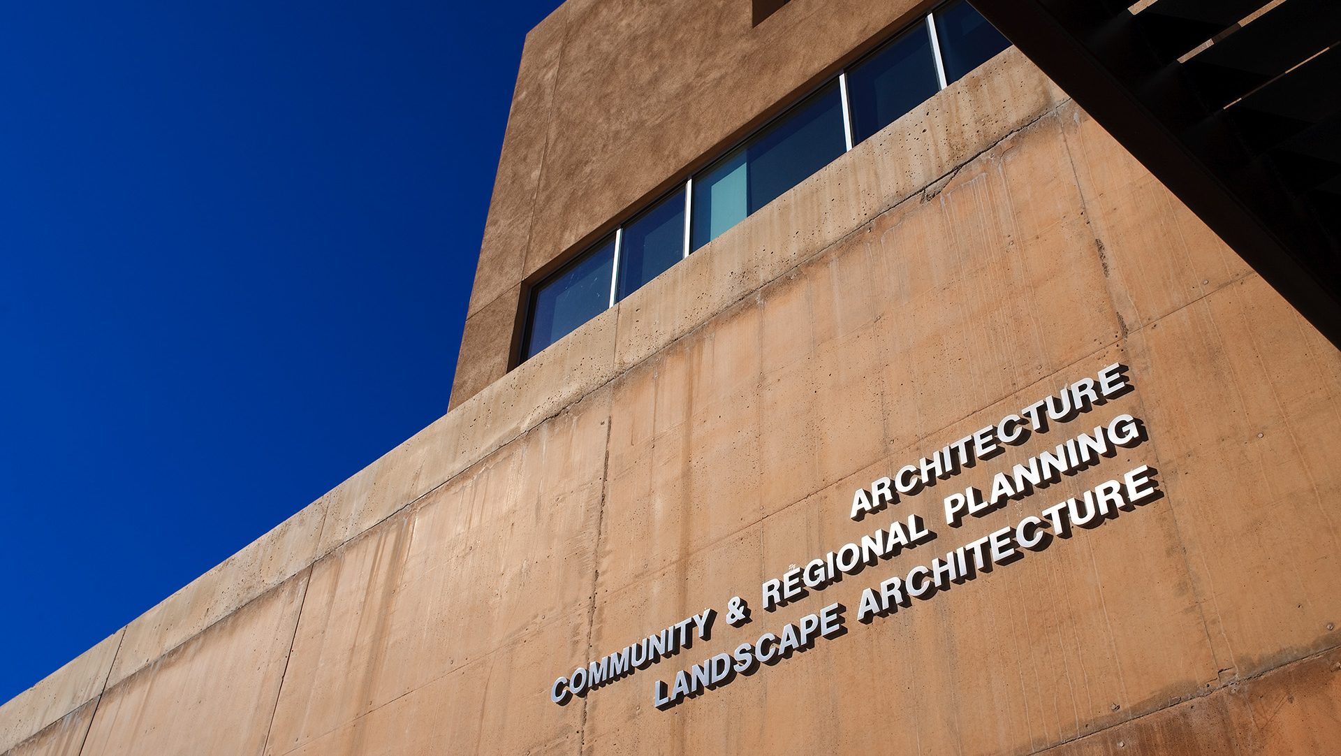 Exterior cast aluminum building letters with brushed satin finish mounted on concrete facade at UNM School of Architecture