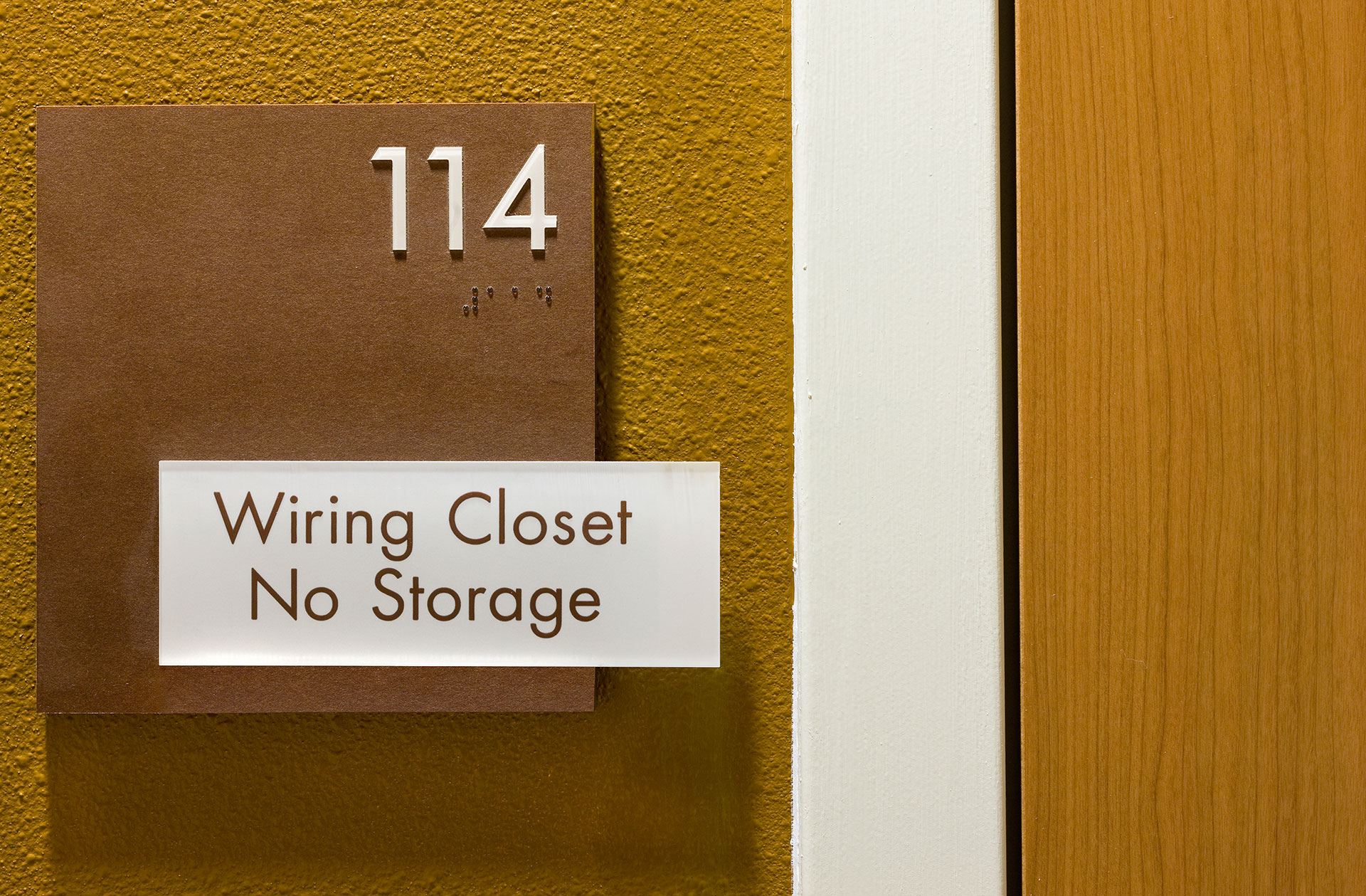Interior ADA room identification sign with tactile letters and braille