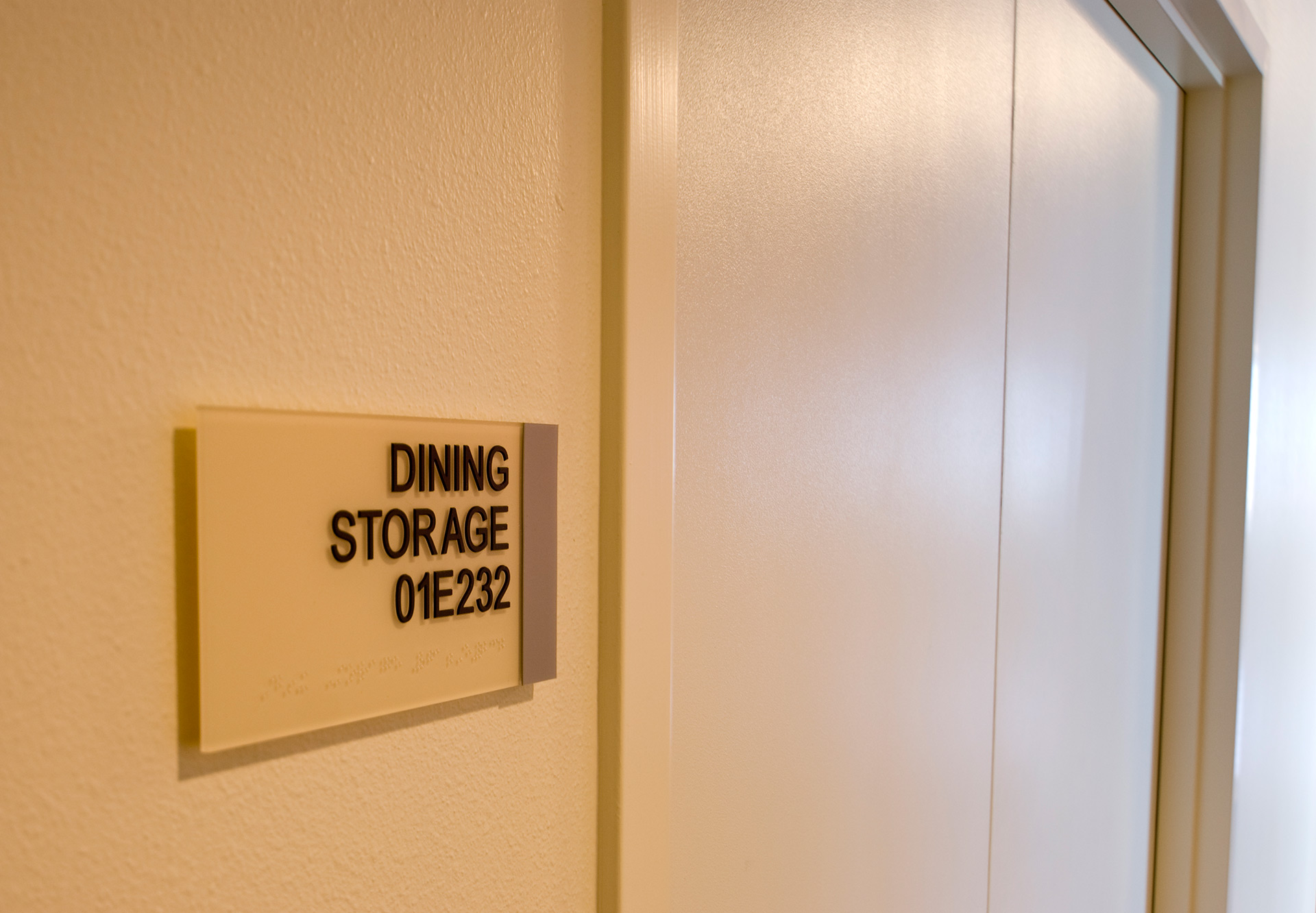 ADA compliant room sign with tactile lettering and braille mounted on wall
