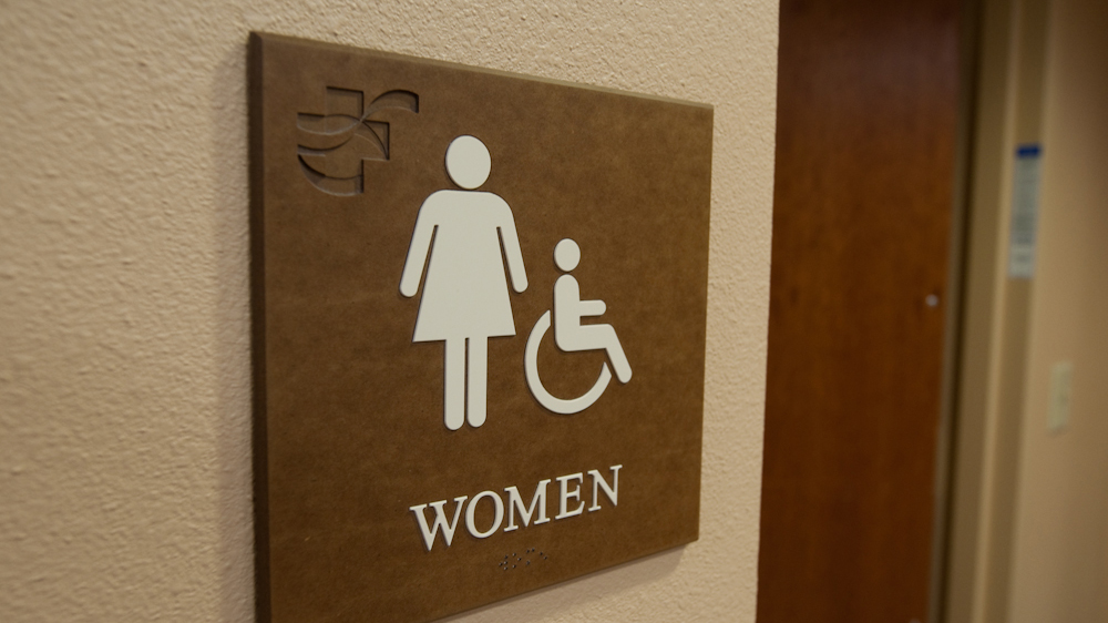 ADA restroom sign with tactile pictogram and engraved logo mounted in healthcare facility