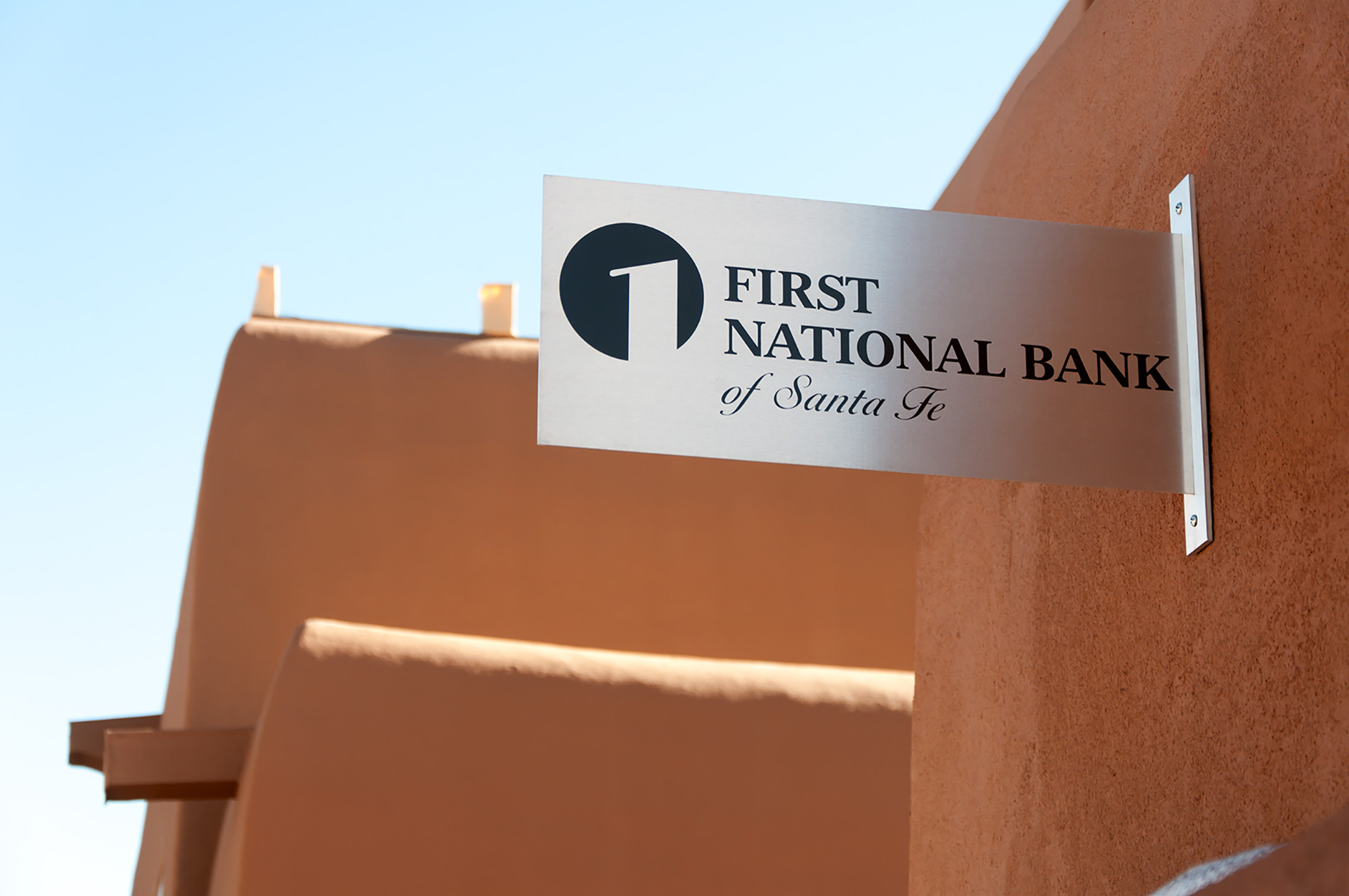 Projecting flag mounted sign for First National Bank Santa Fe exterior wayfinding