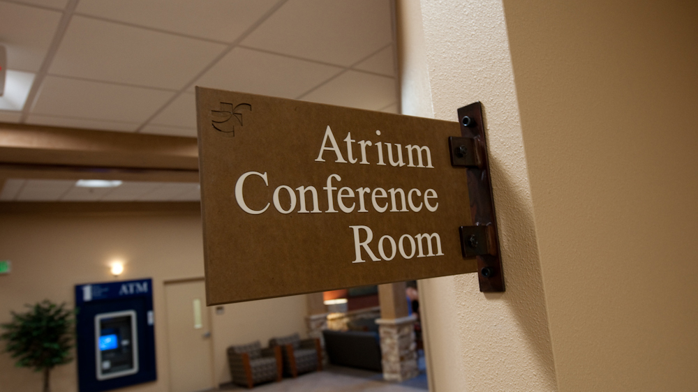 Projecting conference room identification sign with decorative mounting bracket and texture finish