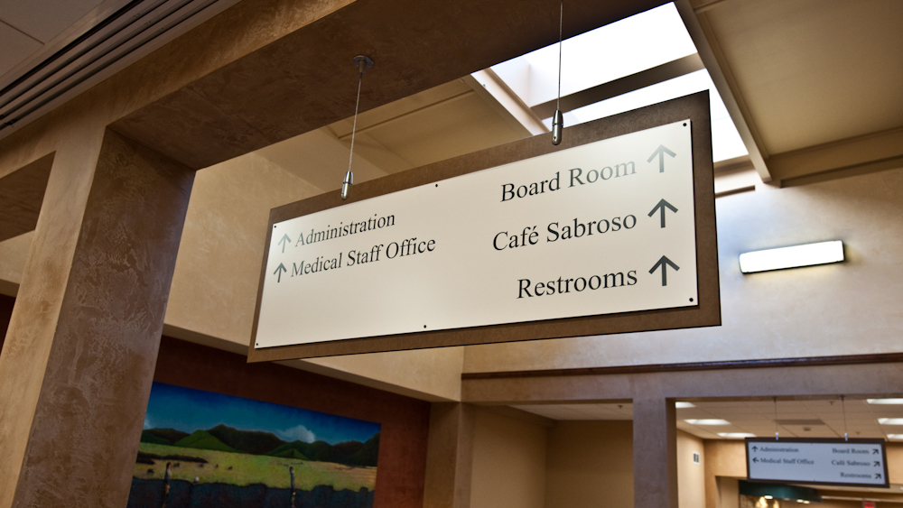 Large suspended hospital directional sign guiding visitors to departments and amenities