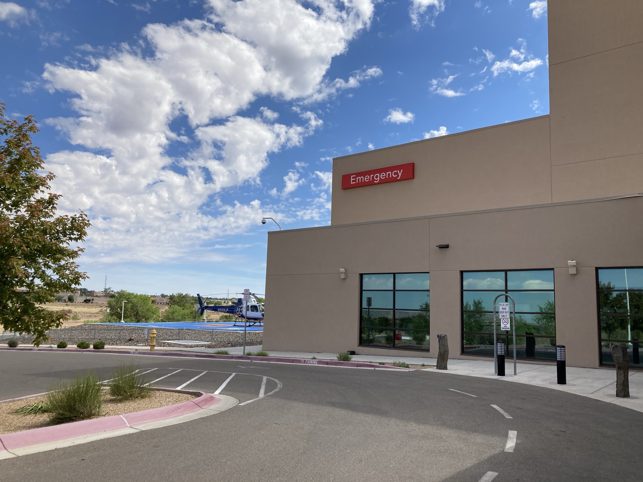 Wall-mounted red emergency sign on the exterior of Presbyterian Santa Fe Medical Center near the emergency entrance.