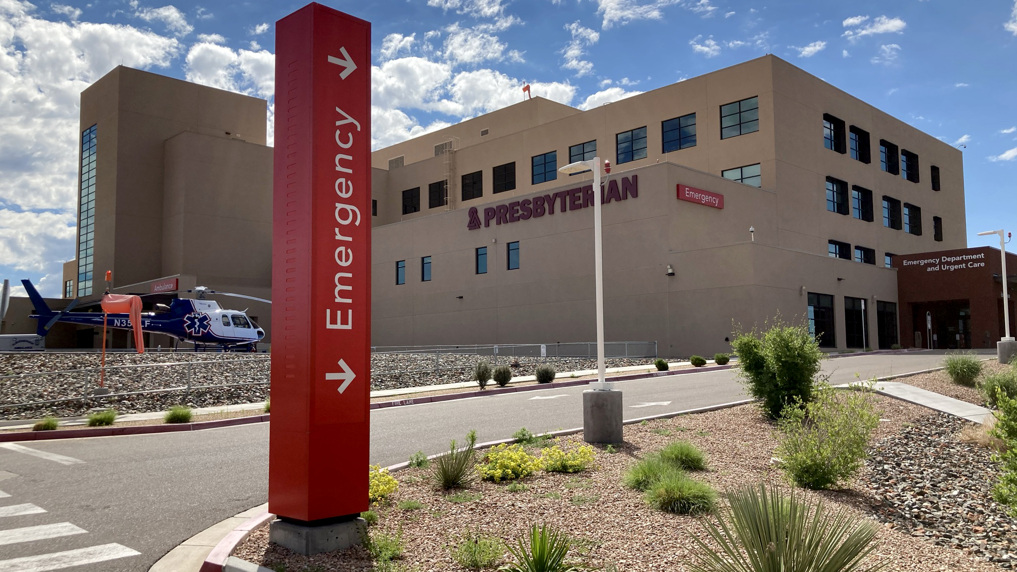 Red exterior emergency wayfinding pylon sign at Presbyterian Santa Fe Medical Center directing vehicles to the emergency entrance.