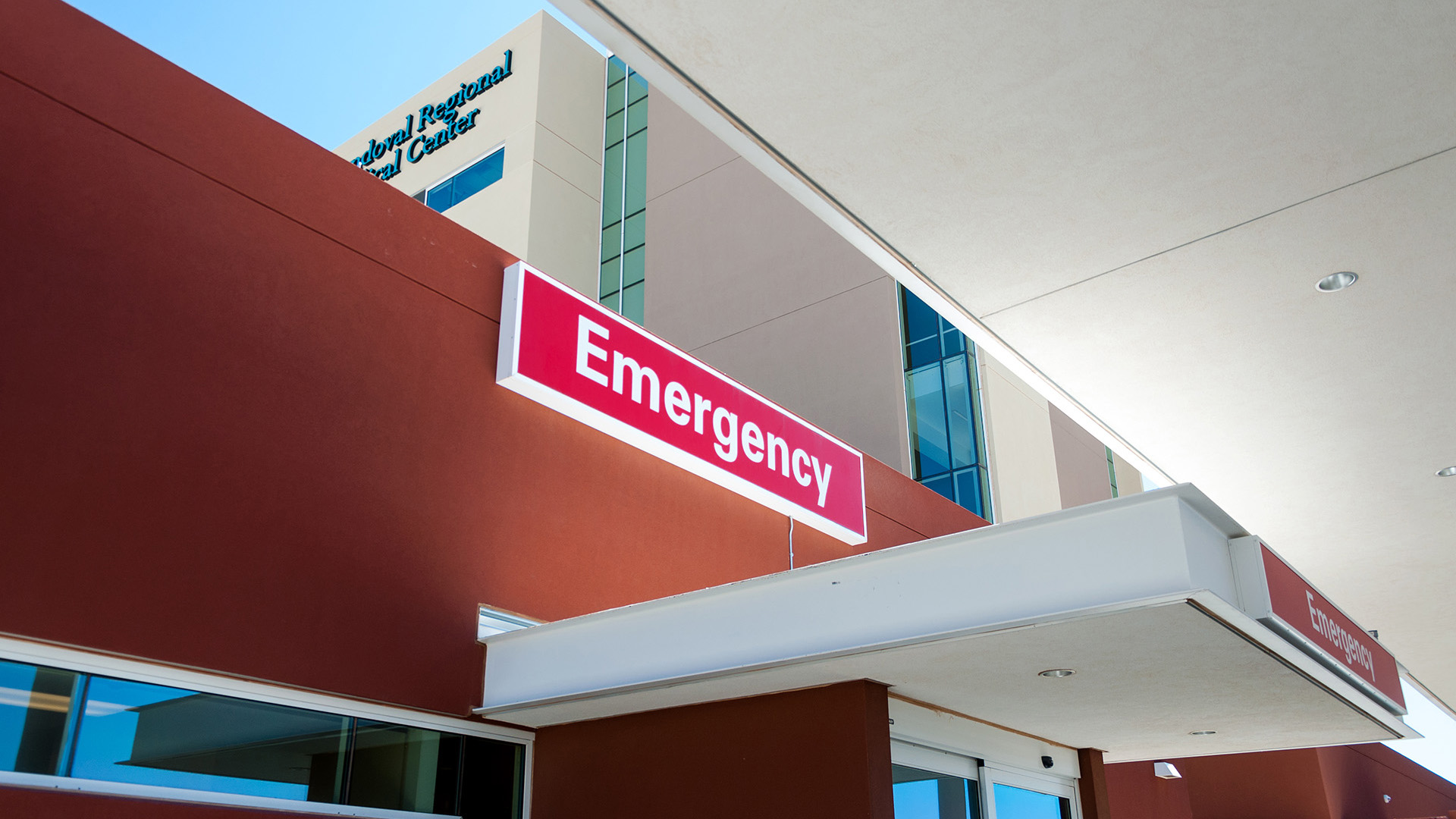 Wall-mounted emergency entrance sign at UNM Sandoval Regional Medical Center