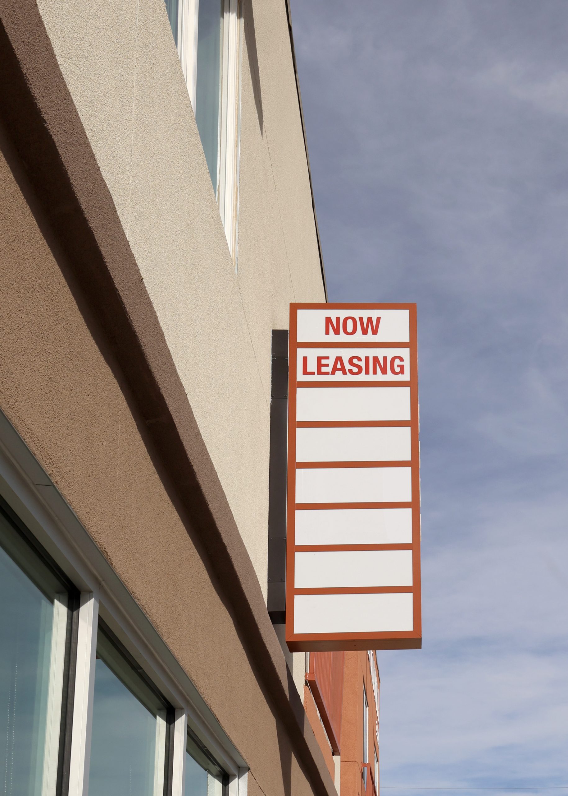 Double-sided illuminated blade sign with changeable tenant panels at Calle Cuarta Apartments in Albuquerque, New Mexico.