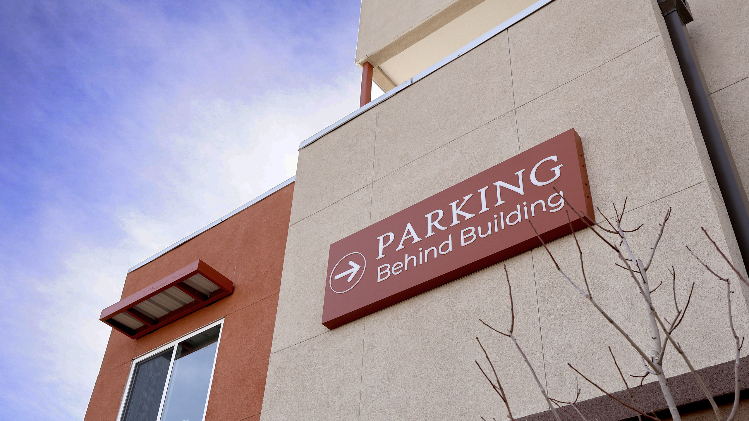 Illuminated parking directional sign mounted on the exterior of Calle Cuarta Apartments in Albuquerque, New Mexico.