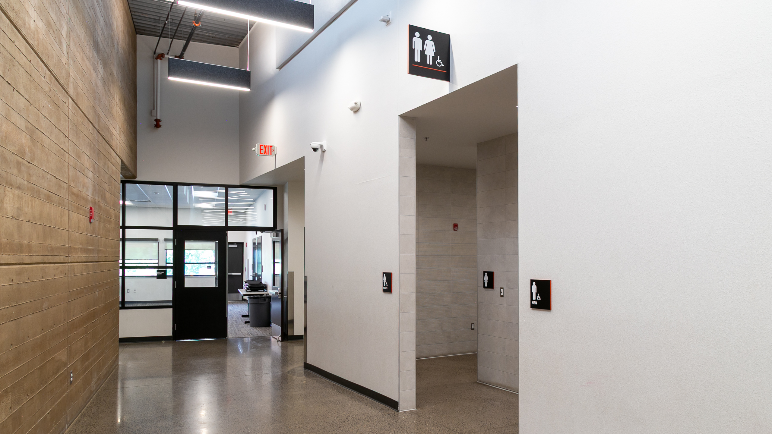 Corridor with flag-mounted and wall-mounted accessible restroom signs