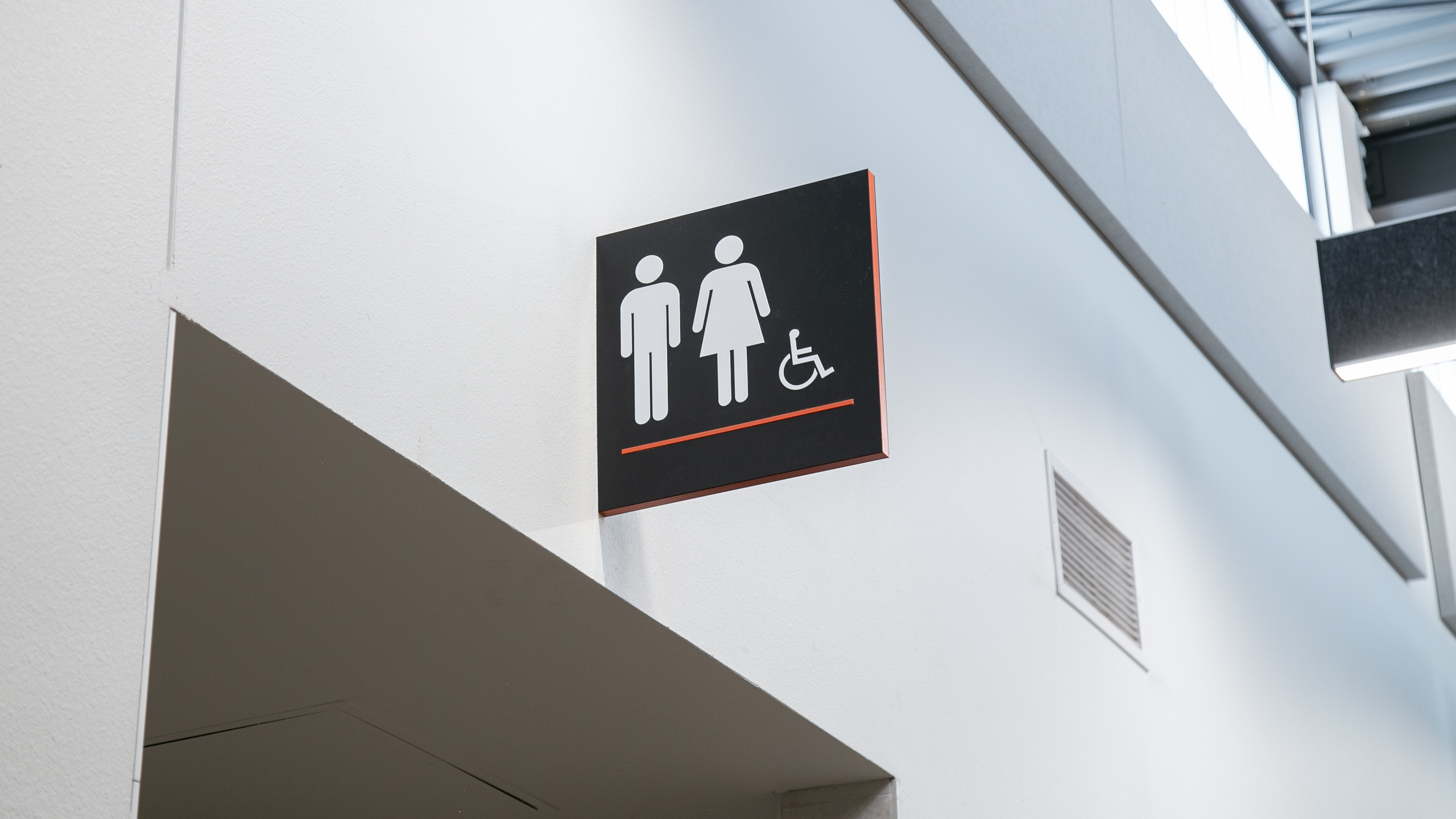 Flag-Mounted Accessible Restroom Sign Black flag-mounted restroom sign with accessibility symbol and orange accent