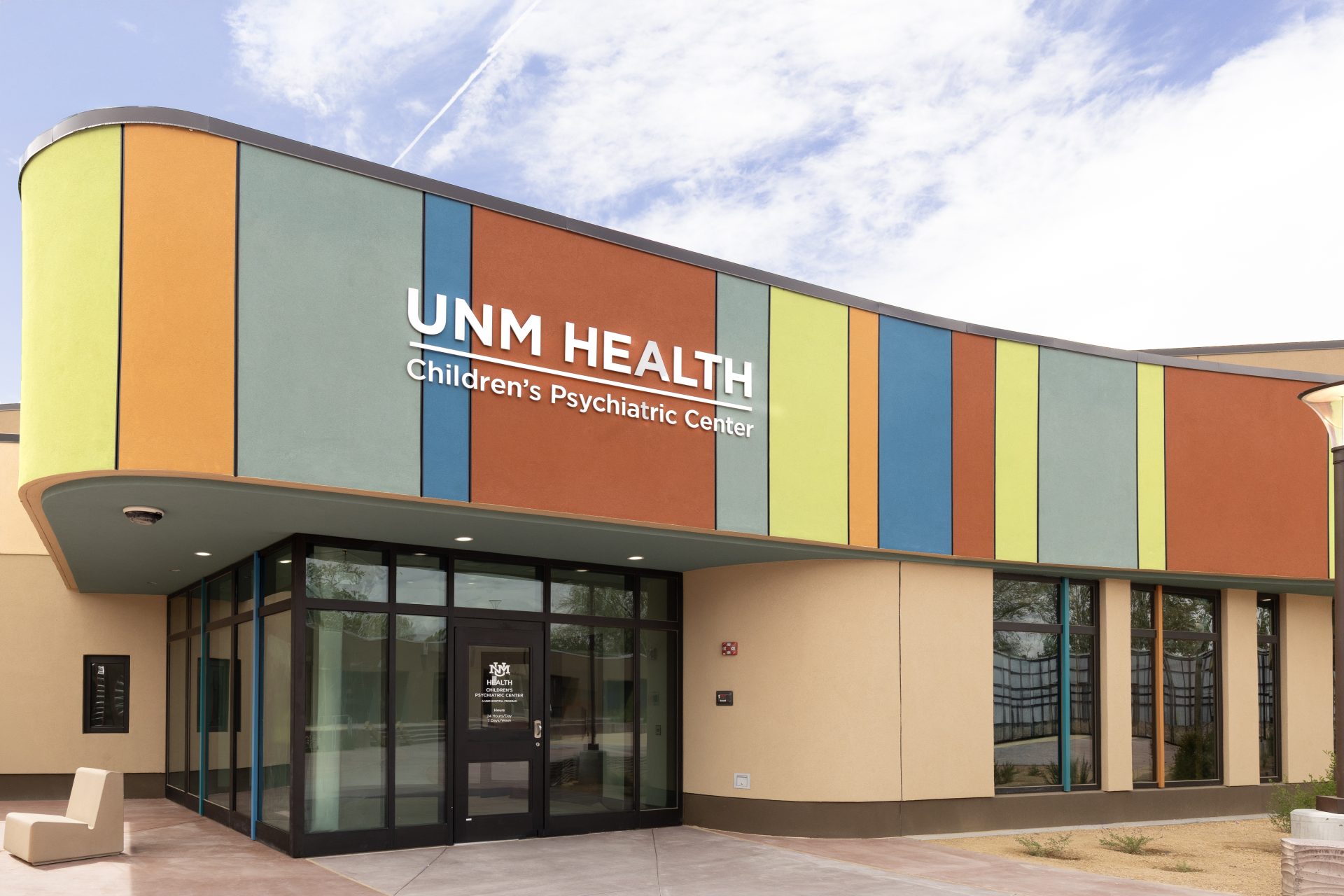 White UNM Health and Children’s Psychiatric Center lettering on a curved, multicolored façade above the entrance.